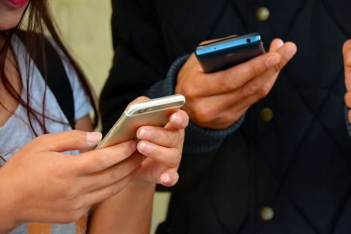 elevi cu telefoanele mobile în mână